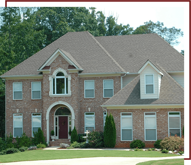 A large brick house with green trees in the background.