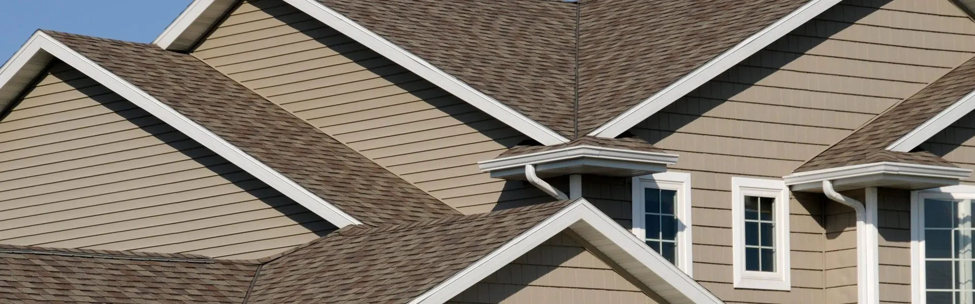 A close up of the corner of a house with brown shingles.