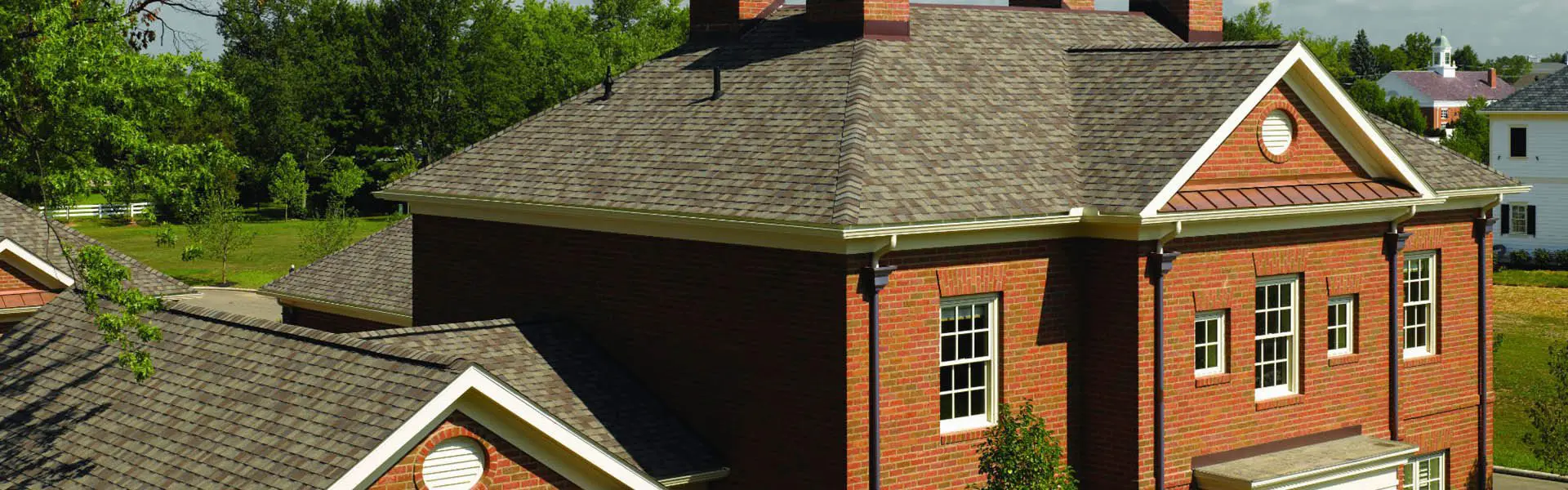 A brick house with a brown roof and white trim.