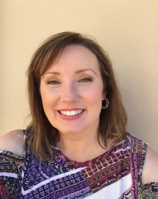 A woman with brown hair and a purple top.