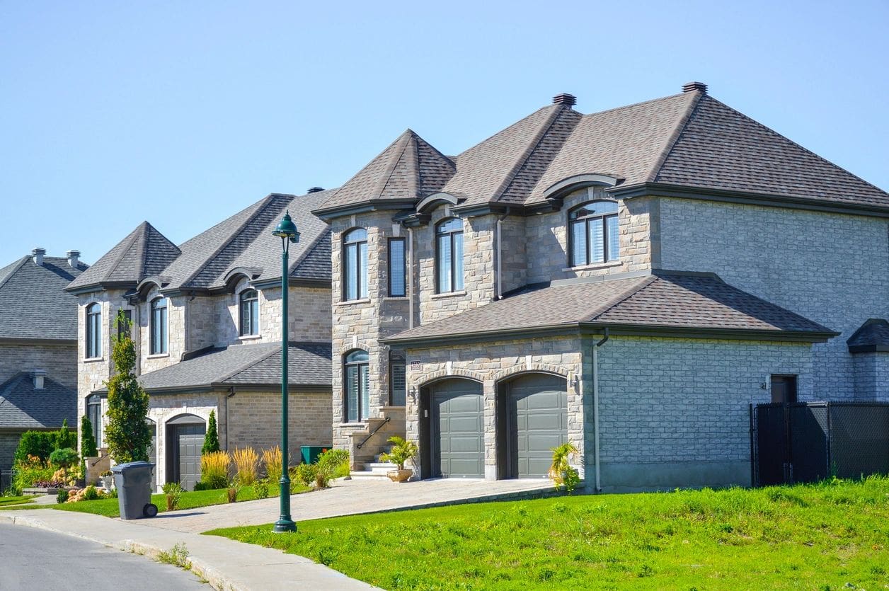 A row of houses with two garages on the side.