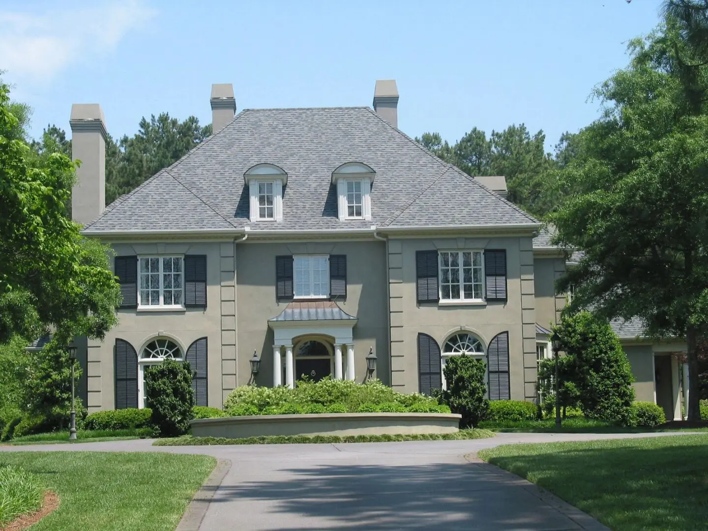 A large gray house with two windows and a driveway.